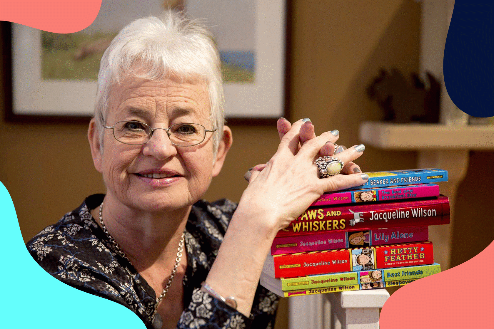 children's author Jacqueline Wilson smiles with a pile of her published books